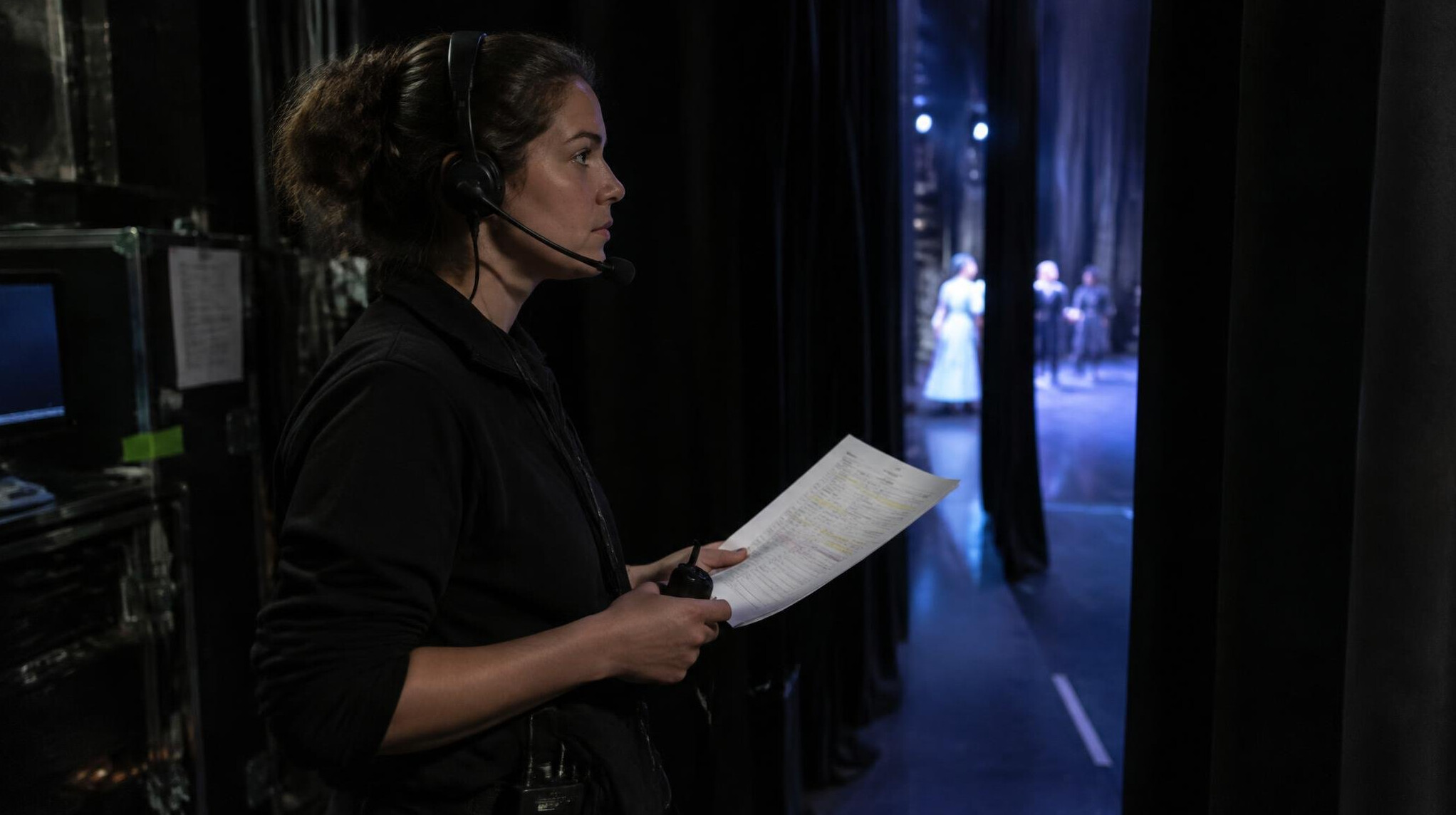 Stage manager reading a cue sheet backstage during a live performance