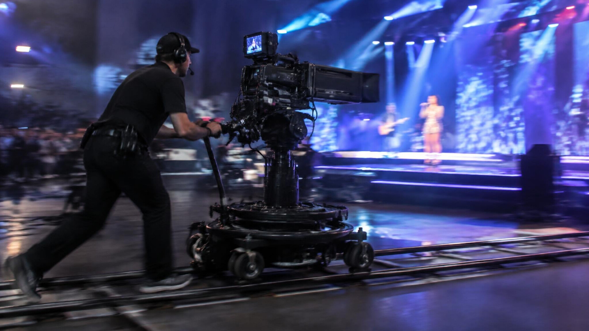 Camera operator moving a broadcast camera on a dolly during a live event